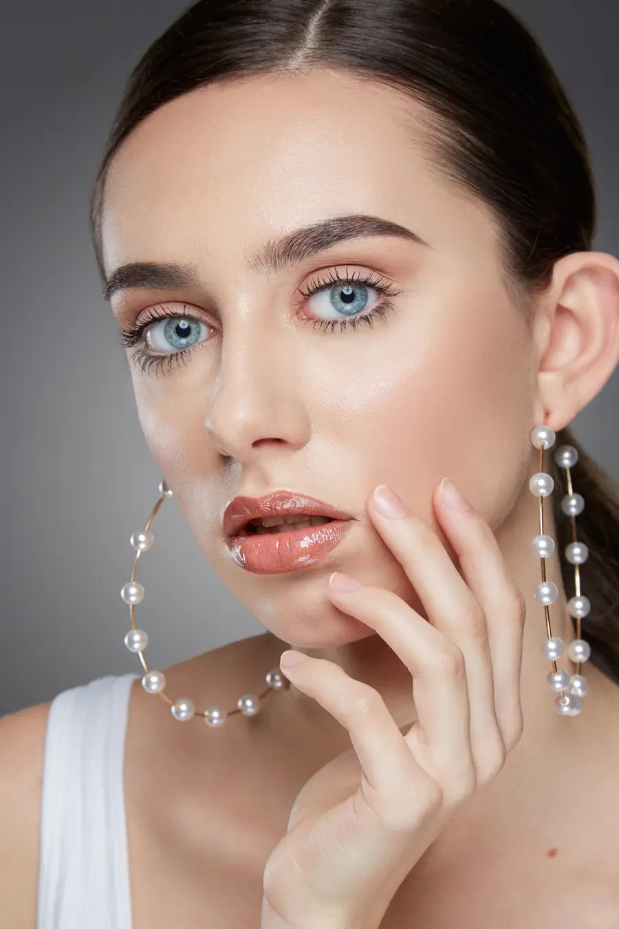 Close-up of prepped skin with soft natural makeup and pearl earrings.