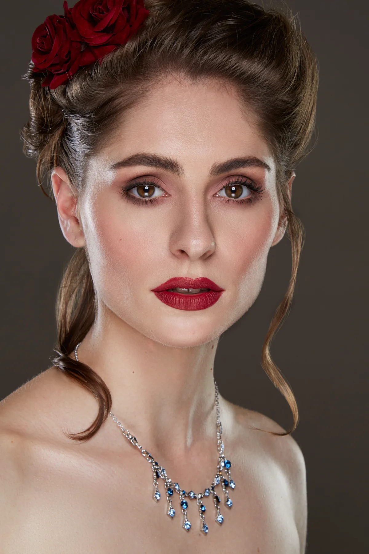 Social beauty look with red lipstick and hair decorated with flowers.